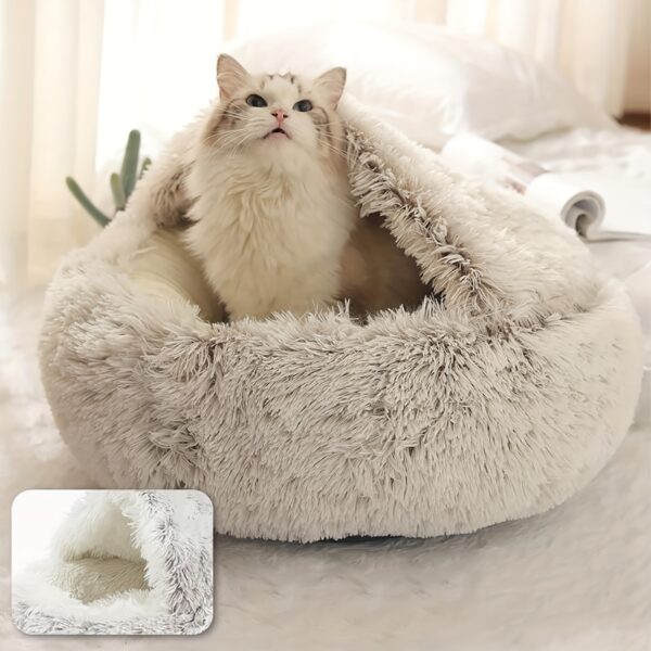 Chat à poil long de couleur crème émergente d'un nid douillet en fausse fourrure blanche.