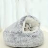 Chat tigré reposant dans un nid pour chat en fausse fourrure grise.